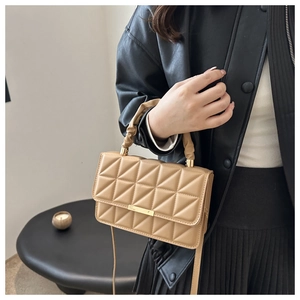 Detail of khaki quilted crossbody bag with triangular stitching and pleated handle