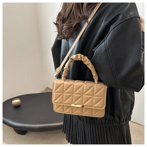 Detail of khaki geometric quilted handbag with pleated handle and metal bar closure