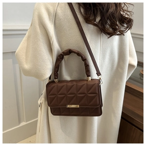 Detail of a brown quilted crossbody bag with a gold buckle and ruched top handle