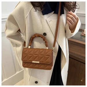 Brown quilted handbag with triangle pattern and ruched handle worn by model on shoulder