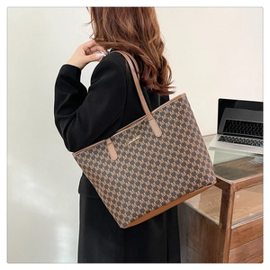 Détail d'un grand cabas vintage avec motif monogramme 'M' et anses en cuir marron