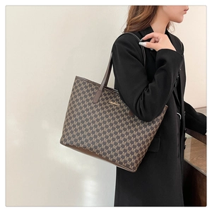 Détail du sac cabas monogramme vintage avec anses en cuir et plaque logo métal
