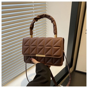 Close-up of geometric quilted dark brown crossbody bag with pleated handle and gold hardware