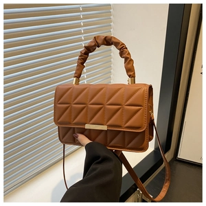 Detail of caramel brown quilted bag with ruched handle and golden magnetic buckle