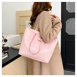 Detail of pink monogram tote bag with gold metal logo and dual handle straps