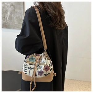 Detailed side view of an ethnic style drawstring bucket bag with floral patterns