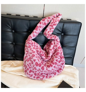 Dettaglio della borsa tote in peluche rosa con stampa leopardata su divano nero in pelle