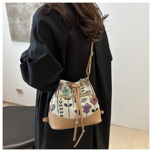 Bohemian floral woven bucket bag with leather base shown on a model for lifestyle view