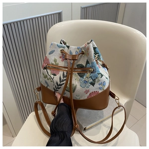 Close-up of vintage floral canvas bucket bag with brown leather trim and drawstring closure