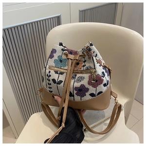Detailed macro view of retro floral jacquard bucket bag with brown leather accents