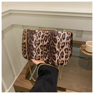 Gros plan du sac en daim léopard avec bandoulière chaîne dorée dans un décor chaud