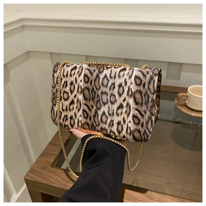 Détail du sac à main léopard avec chaîne dorée posé sur une table de café chic