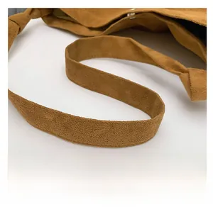 Detail of wide brown suede strap with decorative knot on a minimalist tote bag