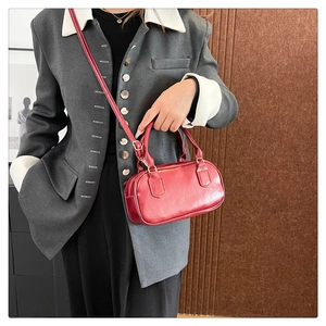 Detail of red vintage-style bowling handbag with smooth finish and removable strap