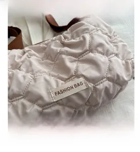 Detail of beige quilted tote showing honeycomb stitching and 'FASHION BAG' woven label