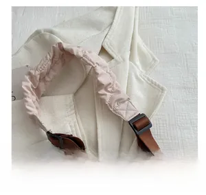 Detail of pink quilted puffy handle and adjustable brown nylon shoulder strap on the bag