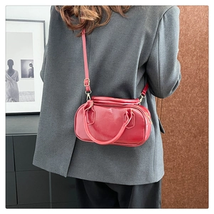 Detail of vintage burgundy bowler bag with golden hardware and adjustable crossbody strap