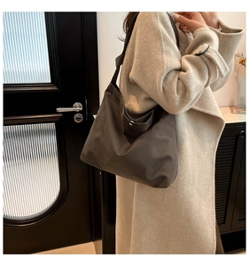 Detail of a large dark grey suede shoulder bag showing textured fabric and slouchy shape