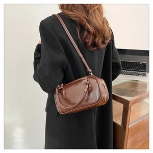 Brown vintage messenger bag with double handles shown worn crossbody on a suit