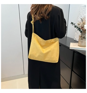 Detail of yellow suede tote bag with knotted strap and silver snap button closure