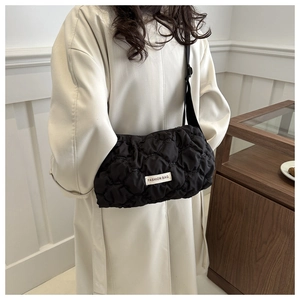 Quilted black puffer tote bag with fashion label shown on a model in a minimalist interior