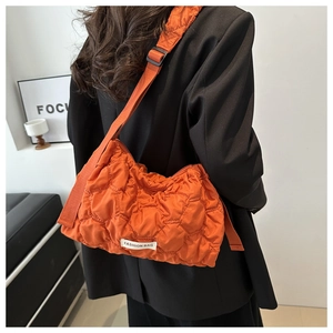 Orange quilted puffy tote bag with fashion label shown on model with black blazer