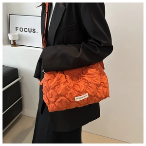Detail of orange quilted nylon tote bag with fashion label and crossbody strap