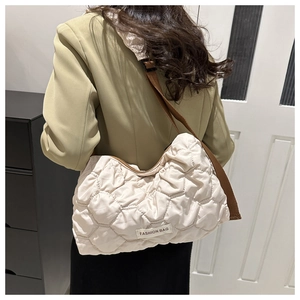 Side view of model wearing a beige quilted puffer tote bag with brown shoulder strap