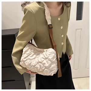 Detail of the cream-white quilted tote bag with brown shoulder strap and fashion label