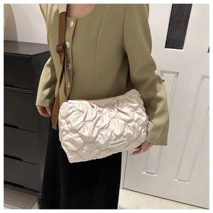 Close-up of beige quilted puffy tote bag with fashion label and adjustable strap