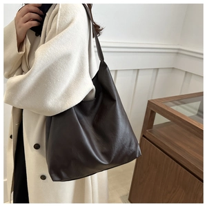Close-up of deep chocolate tote bag with smooth leather texture on a model shoulder