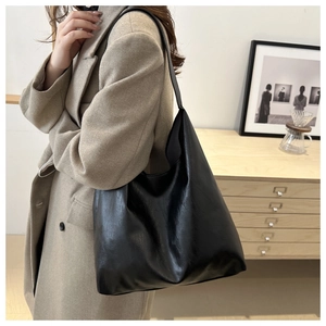 Retro black oversized tote bag worn with beige wool coat in a cozy minimal room
