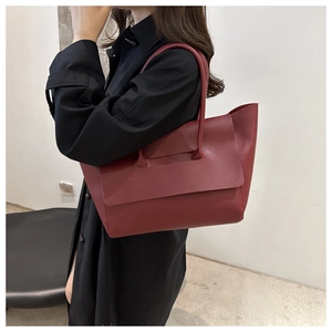 Macro shot of a minimalist burgundy leather tote bag showcasing its matte texture and flap