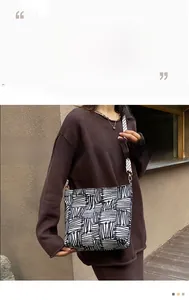Detail of canvas tote bag with black and white geometric patterns and checkerboard strap