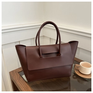 Detail of minimalist dark brown tote bag on a glass table with modern coffee cup setup