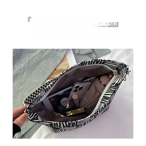 Detailed interior of zebra print tote bag filled with gadgets and daily essentials