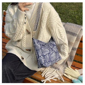 Detail of canvas tote bag with blue abstract lines and checkered wide strap in outdoor setting