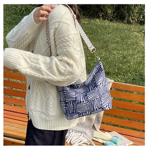 Detail of blue geometric print canvas tote bag with textured crossbody strap shown on model