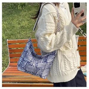 Detail of blue geometric canvas tote bag with check pattern strap in outdoor setting