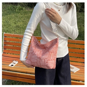 Pink abstract print canvas tote bag with geometric patterned strap on outdoor bench