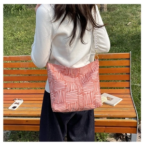 Outdoor view of a large canvas tote bag with pink geometric stripes and polka dot strap