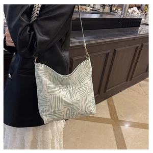 Close-up of light green canvas tote with white abstract patterns and metal buckle strap