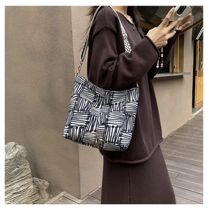 Detail of canvas tote bag showing black geometric lines and checkerboard pattern strap