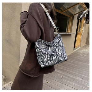 Detail view of canvas tote bag with abstract stripes and check pattern strap on model