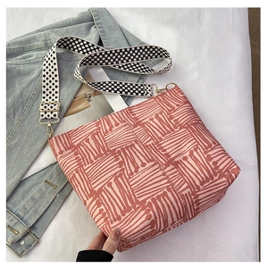 Pink canvas tote bag with red stripes and geometric checkerboard strap detail shot