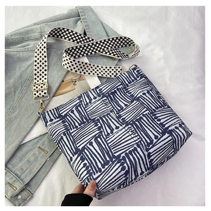 Close-up of geometric blue striped canvas tote bag with floral print wide shoulder strap