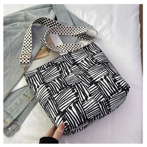 Detail of black and white striped tote bag with floral strap on blue denim jacket