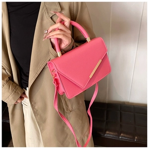 Detail of rose red lychee leather crossbody bag with elegant gold metal bar accent