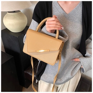 Detail of camel textured leather crossbody bag with elegant gold metal buckle accent