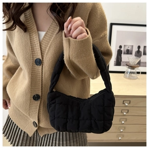 Détail d'un sac sous le bras noir matelassé avec texture bulle douce et fermeture éclair